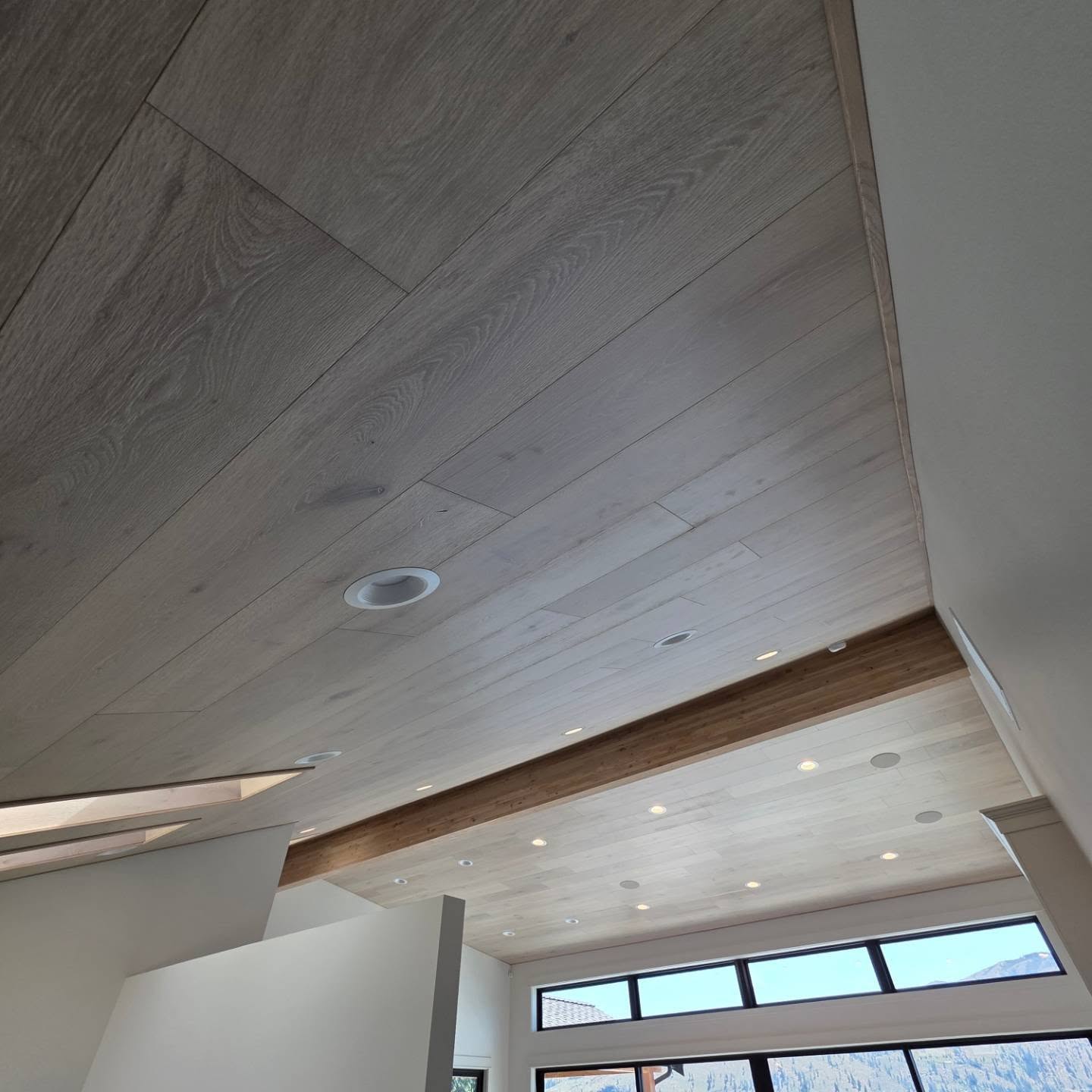 White oak ceiling install in a Manson lake home with exposed wood beam and recessed cans