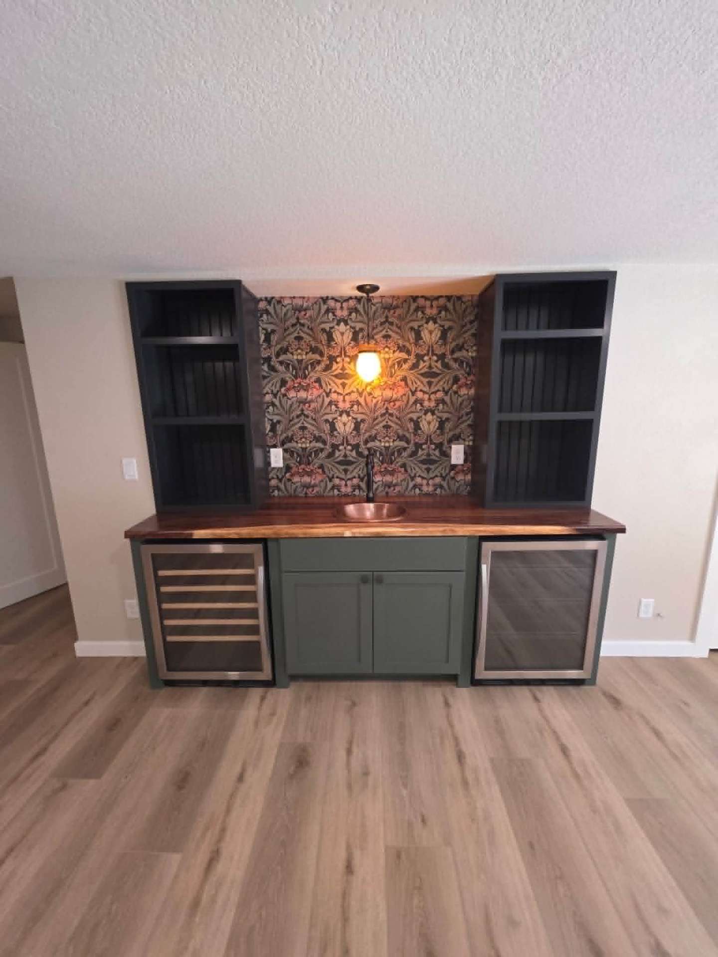 Built-in bar with sage green cabinetry, dual wine fridges, and William Morris wallpaper in Chelan WA
