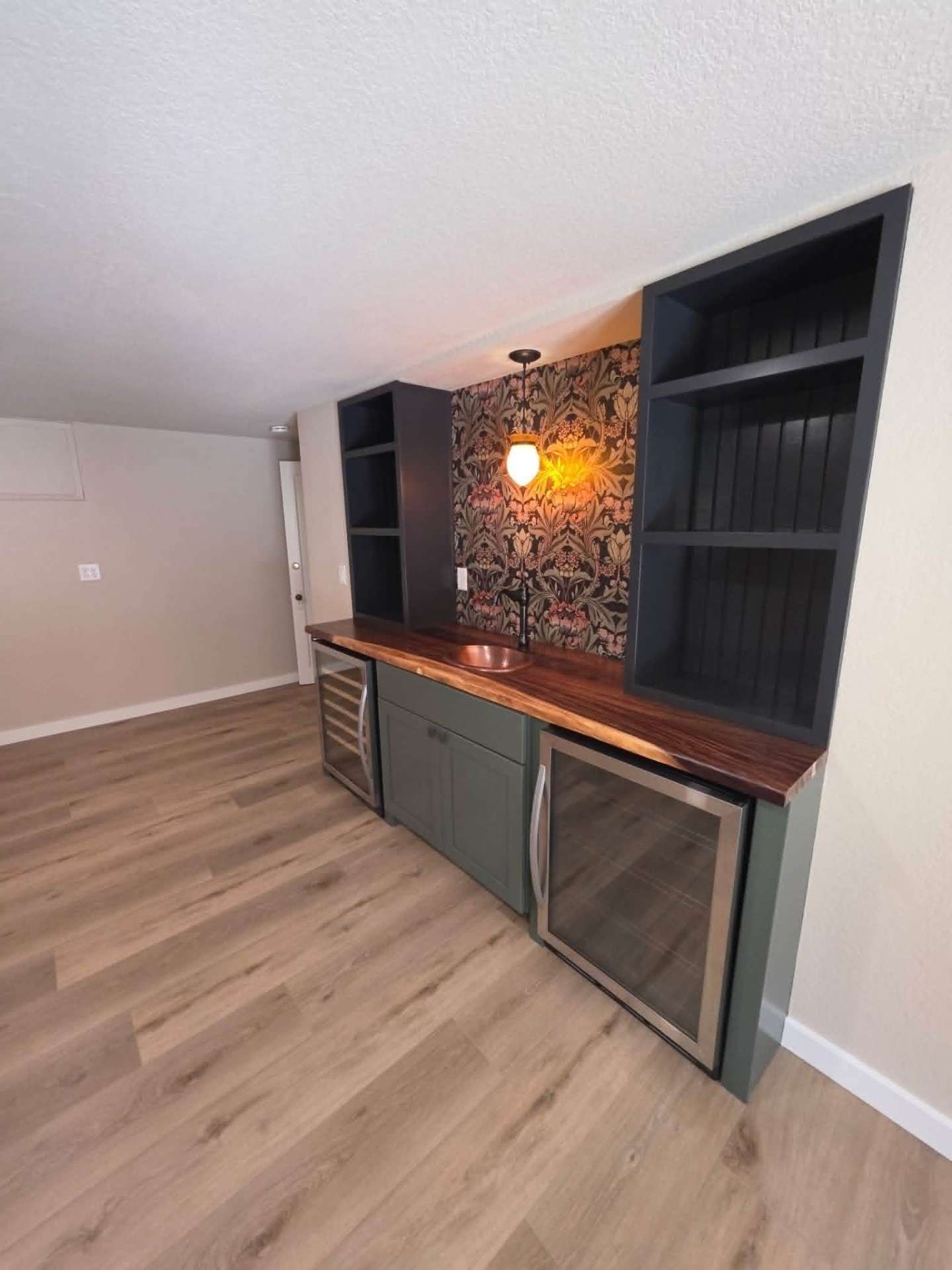 Side view of custom wet bar with paneled black shelving and live-edge countertop in Chelan home