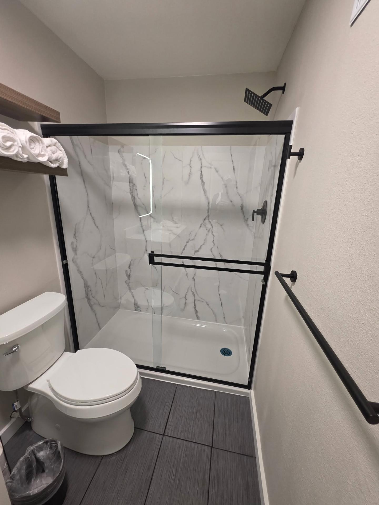 Marble-look shower surround with black trim and tile floor