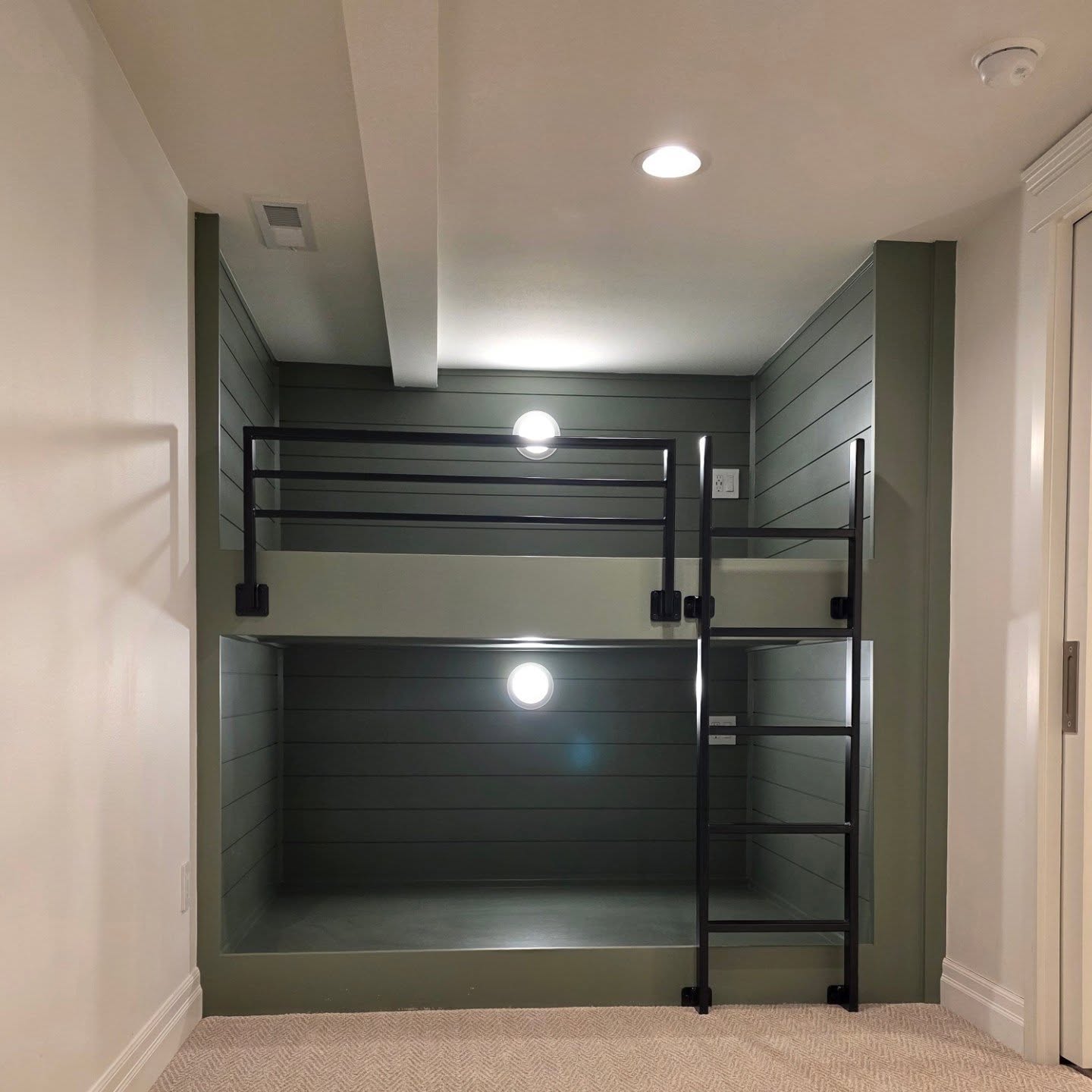 Custom built-in bunks with matte black guard rail, ladder, and recessed lighting in Manson WA