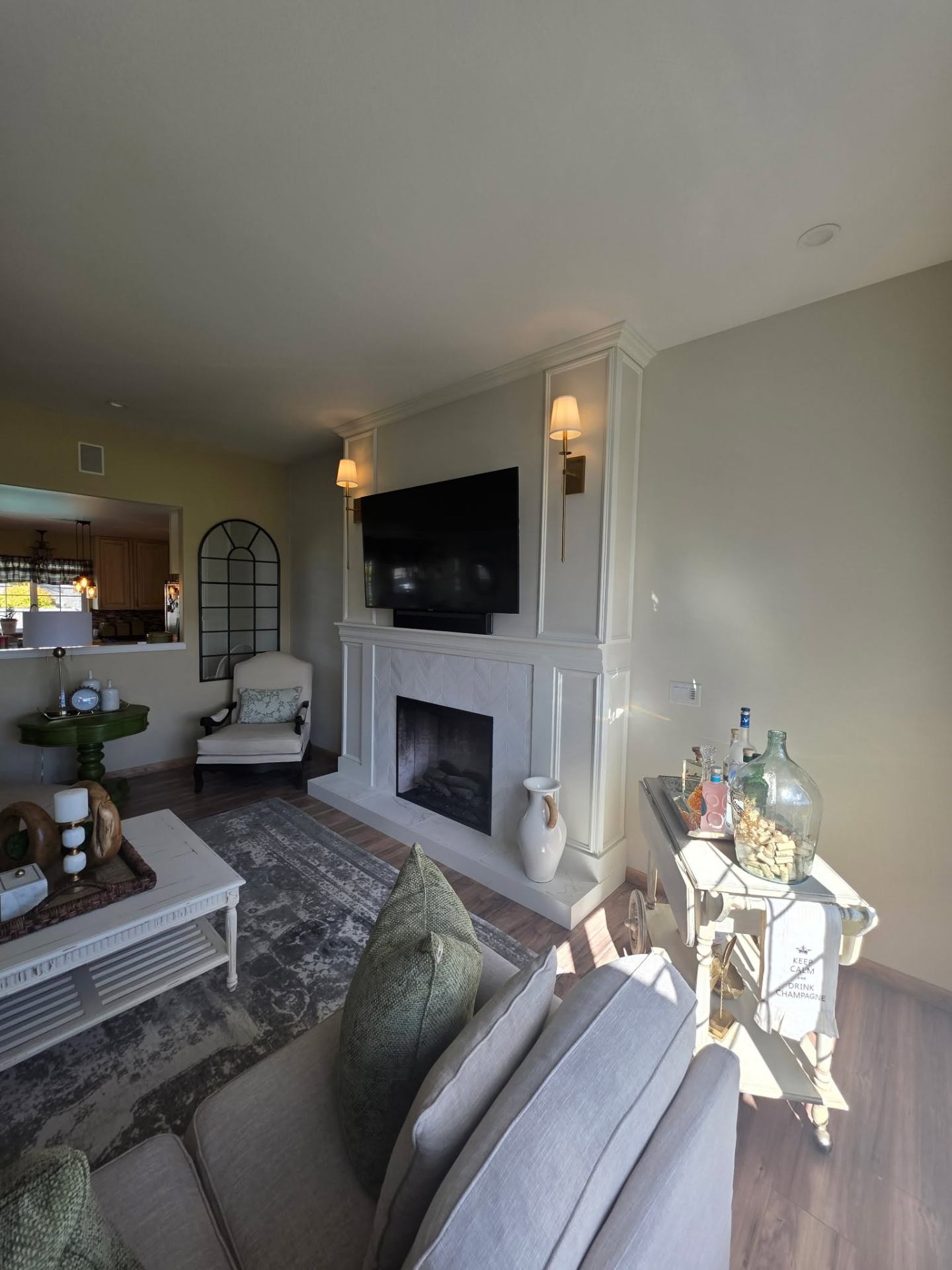 Living room with custom fireplace, paneled wall, and brass wall sconces