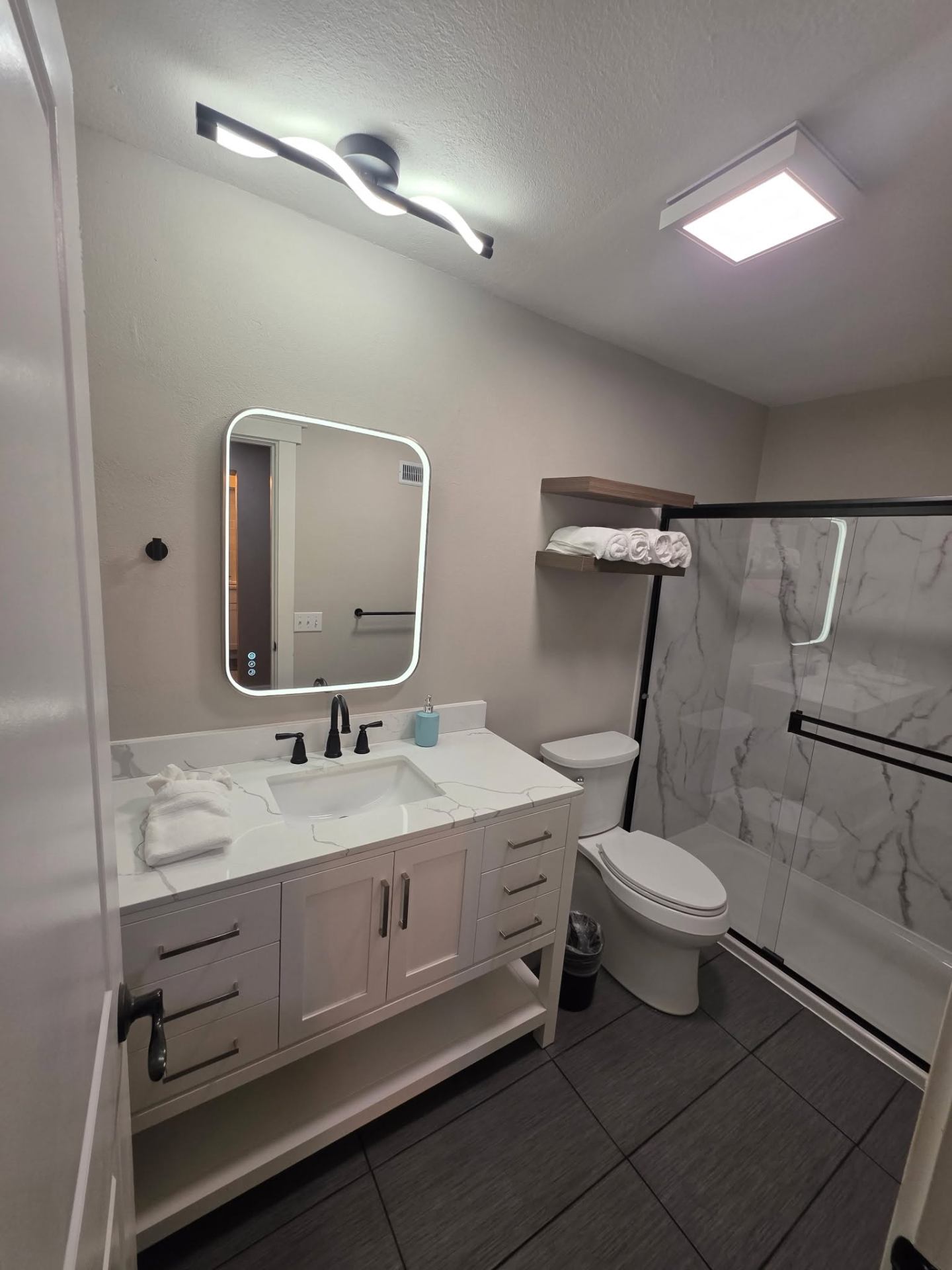 Modern bathroom remodel with quartz vanity and marble-look walk-in shower